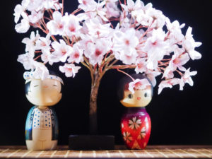 Deux kokeshis sont sous un cerisier en fleur